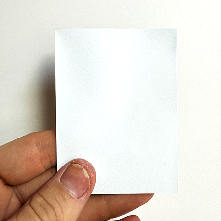 White opaque-back TCG card sleeve holding a playing card